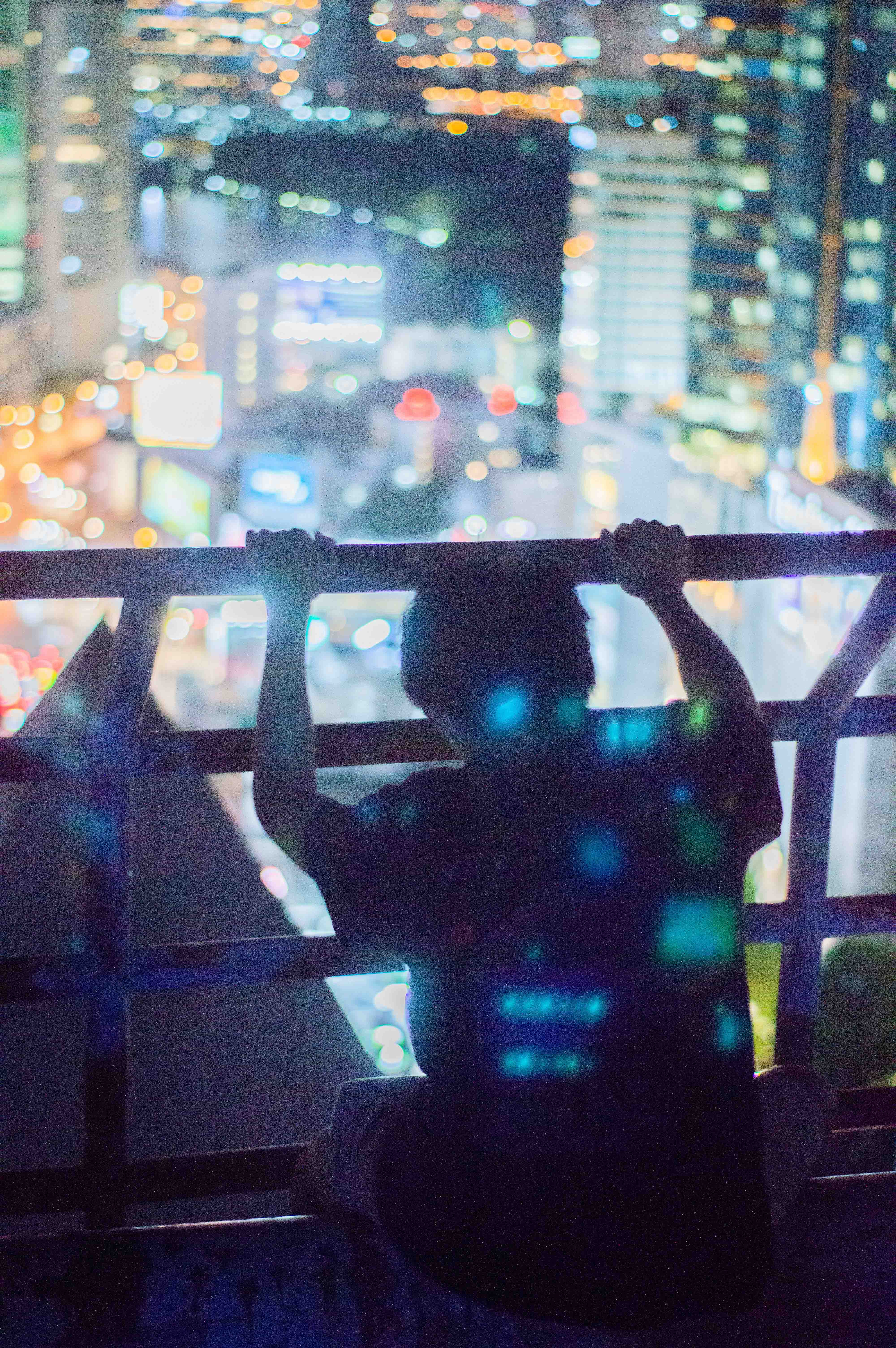 Man sits upon skyscraper at night, Bangkok 